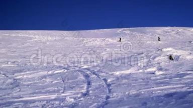 两个滑雪者在一个山脉的背景下降落在一个雪坡上。 在大雪纷飞的冬天，<strong>危险</strong>的自由